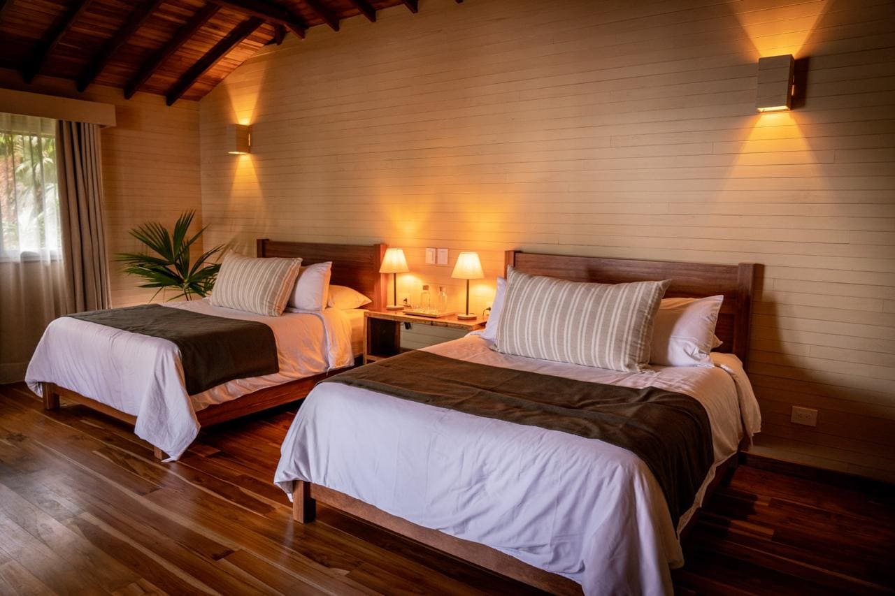 Habitación cálida con dos camas, lámparas tenues y piso de madera