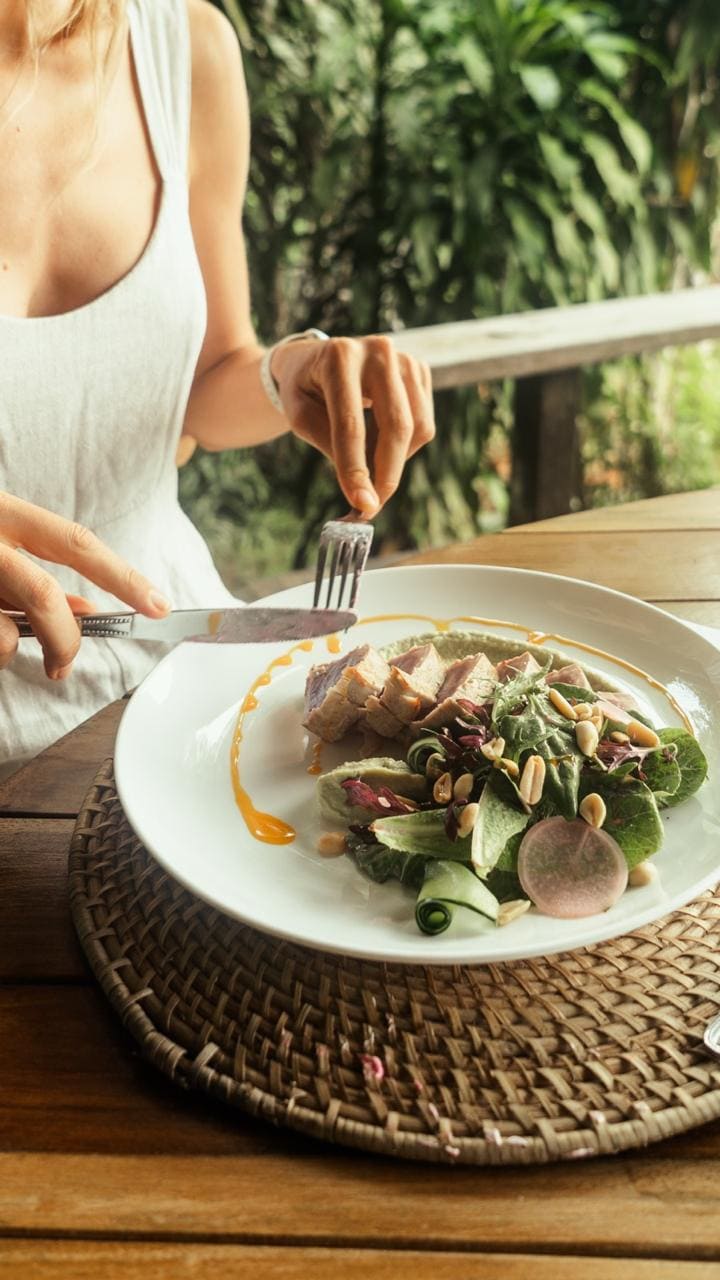 Persona disfrutando un plato en una mesa de madera frente a la selva